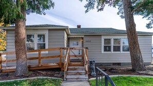 A house with a wooden staircase leading to a front door, surrounded by trees and a well-maintained lawn. - Kimball Cottage (Richland)