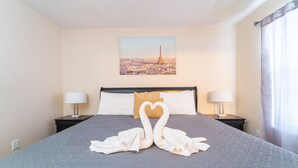 A hotel room with a bed, two nightstands, a painting of the Eiffel Tower, and a heart-shaped towel arrangement. - Regal Palms Resort  Communal Pool, Arcade, Fitness Center & Tennis (Davenport)
