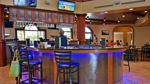 A bar area with a curved counter, bar stools, and a television mounted above. - Regal Palms Resort  Communal Pool, Arcade, Fitness Center & Tennis (Davenport)