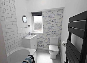 A bathroom with a bathtub, sink, toilet, and a window. - Charming 2-bed Cottage in the Heart of Stanhope (Bishop Auckland)