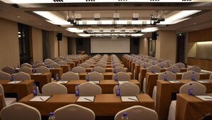 A conference room with rows of tables and chairs, equipped with water bottles and notepads. - Tangyi Hotel Zhuhai (Zhuhai)