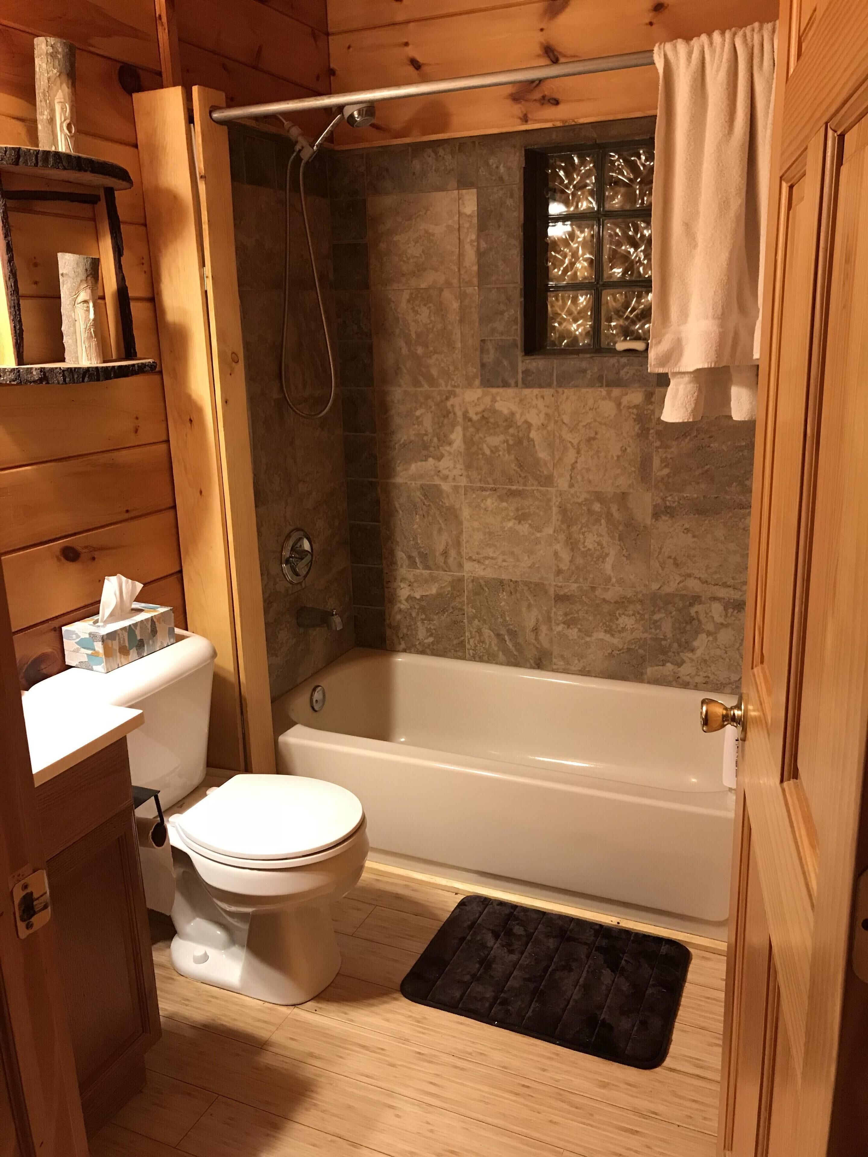 A wooden cabin bathroom with a toilet, bathtub, and shower.