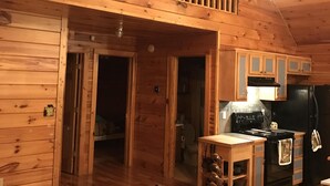 A cabin interior with a kitchen, dining area, and a loft bedroom. - Cabin at Scenic Heights with a hot tub and wi-fi (Campton)