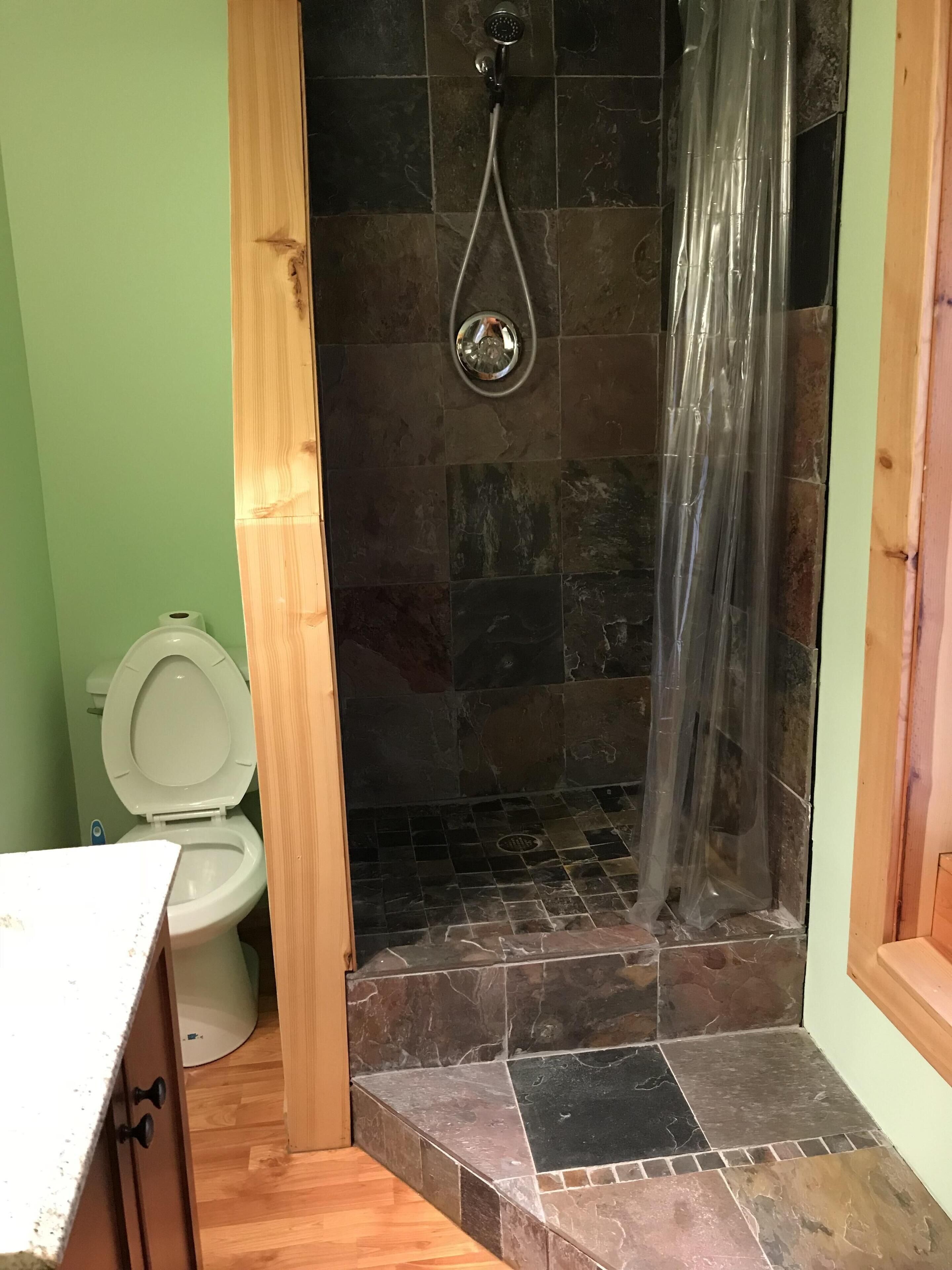 Ein Badezimmer mit Dusche, Toilette und Holzboden.