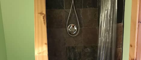 Ein Badezimmer mit Dusche, Toilette und Holzboden.