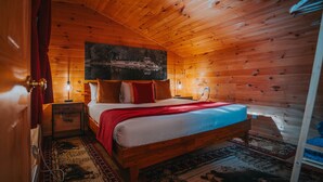 Une pièce chaleureuse, aménagée dans une cabane en bois, avec un lit, une table de chevet, une lampe et un grand tableau accroché au mur.
