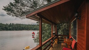 Une terrasse en bois avec une table et des chaises donnant sur un lac.
