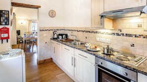 A modern kitchen with wooden cabinets, a stainless steel stove, and a tiled backsplash. - Brook House Farm Cottage (Scamblesby, near Louth)