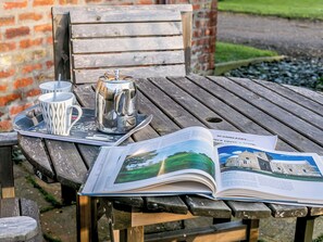 A wooden table with a metal tray holding two cups and a teapot, an open magazine, and a brick wall in the background. - Brook House Farm Cottage (Scamblesby, near Louth)