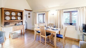 A cozy dining area with a wooden table, chairs, and a built-in shelf with plates. - Brook House Farm Cottage (Scamblesby, near Louth)