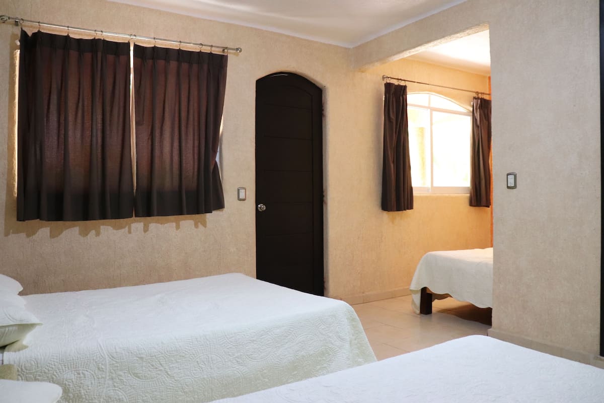 A room with two beds, a door, and a window with curtains.