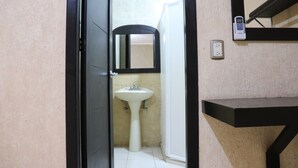 Un baño con un lavabo blanco, un espejo y una encimera negra.