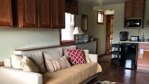 A living room with a beige sofa, patterned cushions, a wooden coffee table, and a floral rug. - Serenity Suite-Private Suite close to downtown (Estes Park)