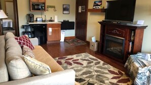A living room with a sofa, a television, a fireplace, and a kitchen area in the background. - Serenity Suite-Private Suite close to downtown (Estes Park)