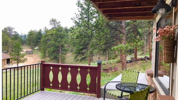 A wooden deck with a red railing, a glass table, and two green chairs. - Serenity Suite-Private Suite close to downtown (Estes Park)