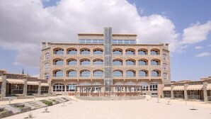 A multi-story building with a central glass tower, surrounded by a courtyard with steps leading to the entrance. - Sama Hotel Al Jabal Akhdhar (Sayq)