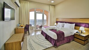 A hotel room with a large bed, a desk, a chair, a TV, and a balcony with a view. - Sama Hotel Al Jabal Akhdhar (Sayq)