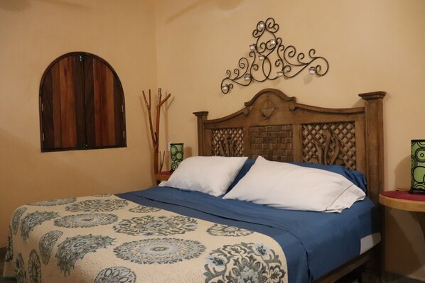 Un dormitorio con una cama, un adorno en la pared y una ventana.