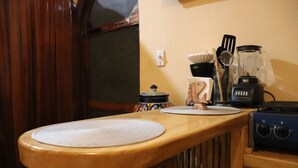 A kitchen with a wooden countertop, a blender, a kettle, and a stove.
