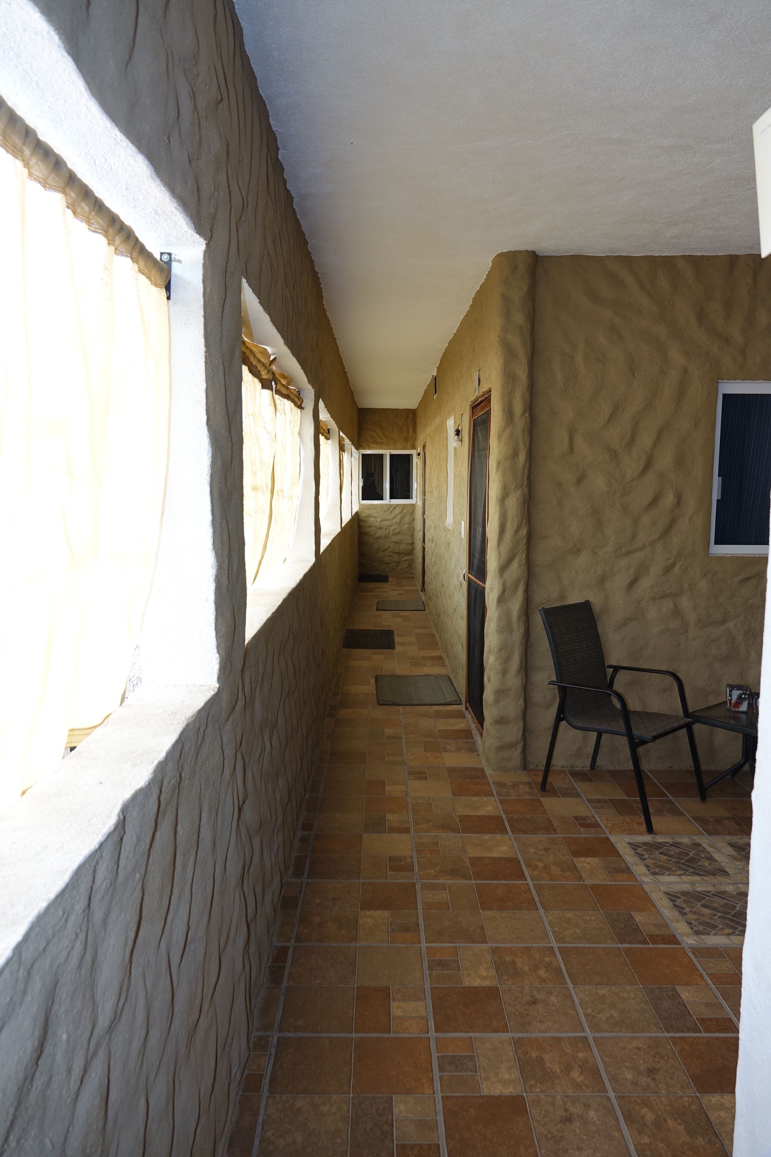 Un pasillo con una silla, una ventana y una puerta.