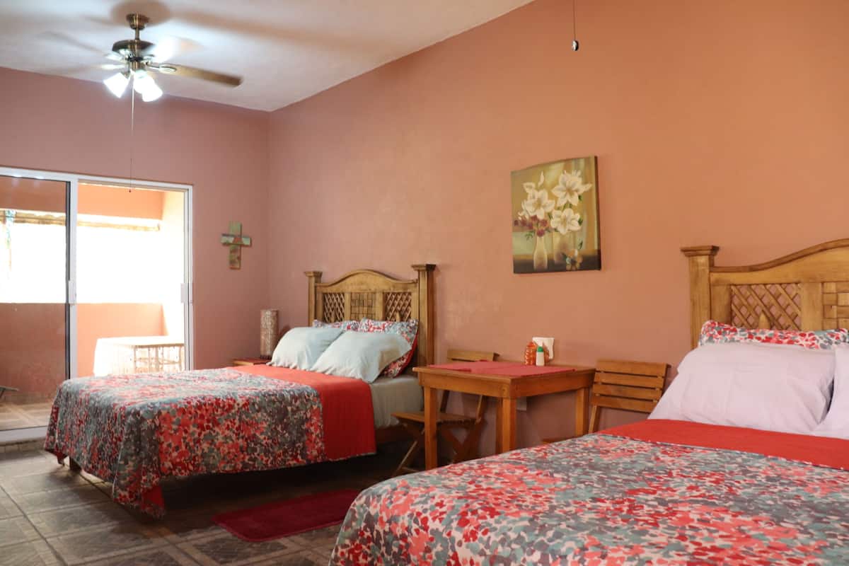 A bedroom with two beds, a ceiling fan, a painting, and a window.