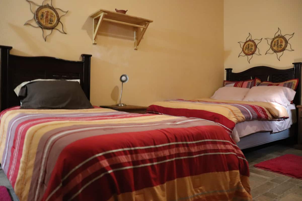 A bedroom with two beds, a nightstand, a lamp, and decorative wall art.