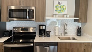 A modern kitchen with stainless steel appliances, wooden cabinets, and a tiled backsplash.