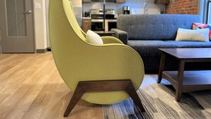 Un salon moderne avec un fauteuil vert, un canapé gris et une table basse en bois.