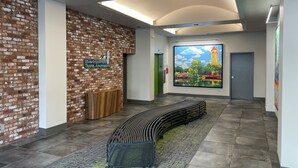 Ein modernes Interieur mit Ziegelwand, einer Bank, einem grünen Aufzug und einem großen Fenster mit Blick auf die Stadt.