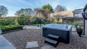 Un bain à remous dans un jardin, avec un mur en pierre et des plantes en pot.