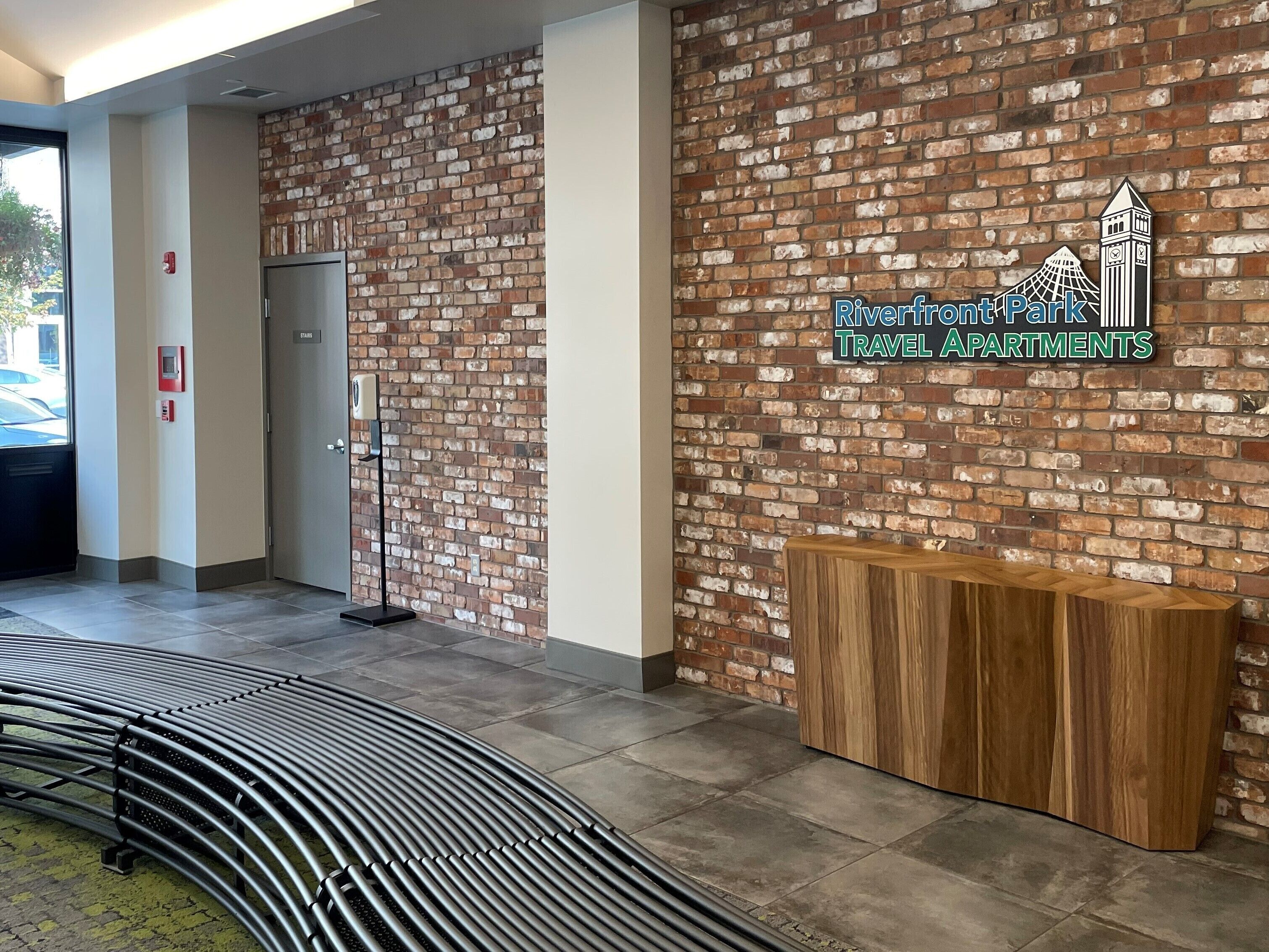 A reception area with a brick wall, a wooden reception desk, and a curved bench.