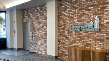 A reception area with a brick wall, a wooden reception desk, and a curved bench.