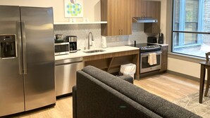A modern kitchen with stainless steel appliances, a built-in oven, and a large window offering a view of the outside.