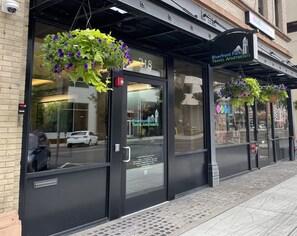 A travel apartment building with hanging flower baskets and a sign indicating it is Riverfront Park Apartments. - Ideal 1 Bed ADA Accessible Travel Apartment in the Heart of Spokane (Spokane)