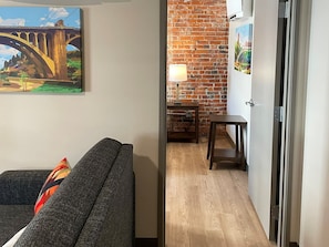 Un salon avec un canapé, une lampe et un mur en briques.