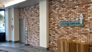 A reception area with a brick wall, a wooden reception desk, and a sign for Riverfront Park Travel Apartments.
