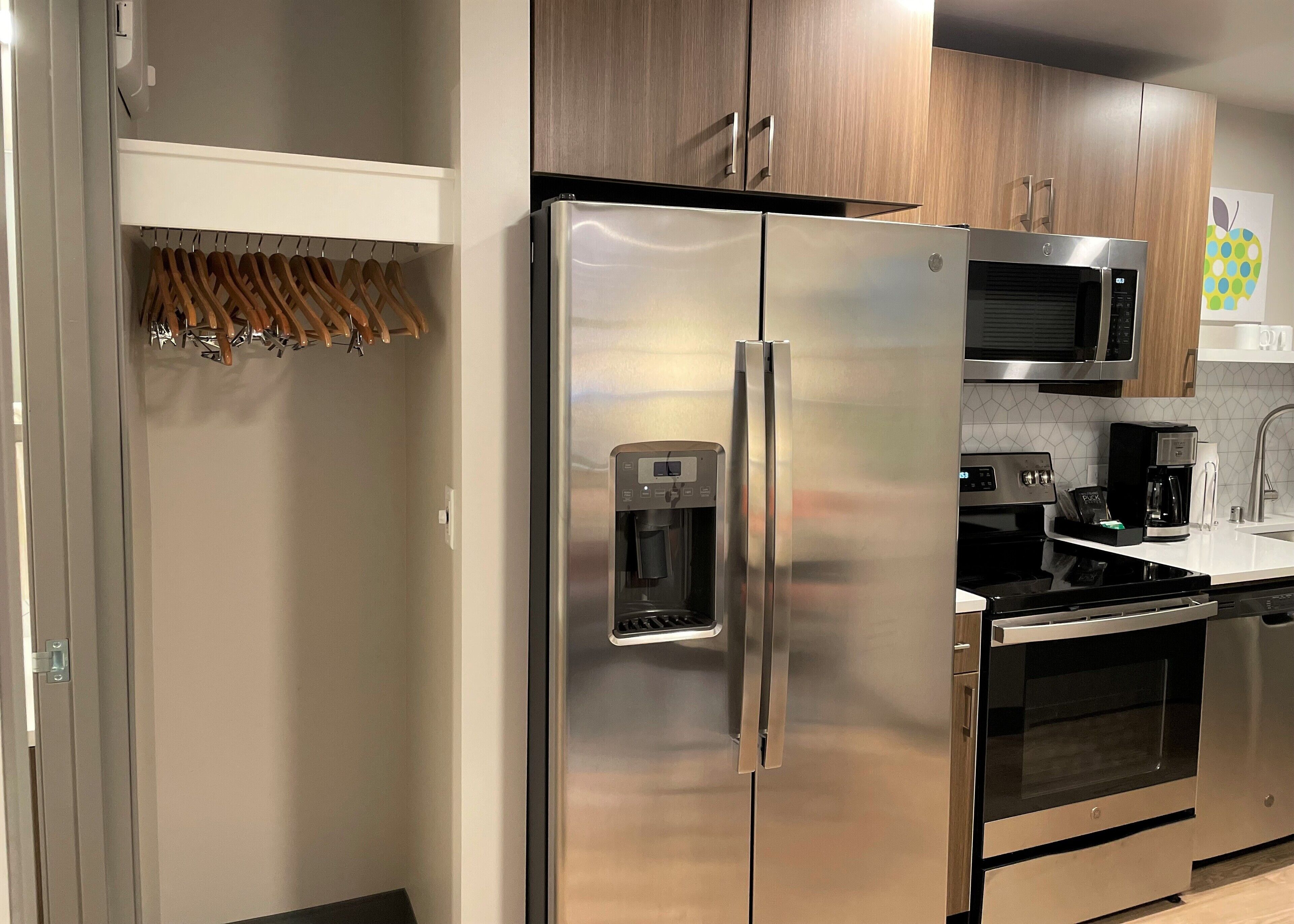 A modern kitchen with stainless steel appliances, a water dispenser, and wooden cabinets.