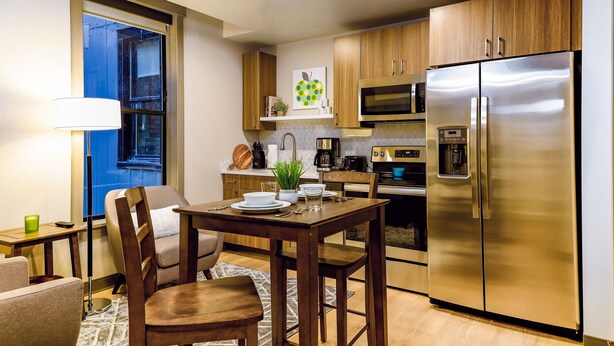 Una cocina moderna con armarios de madera, un refrigerador de acero inoxidable, un microondas y una cafetera.