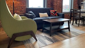 A living room with a sofa, a green armchair, a coffee table, and a lamp.