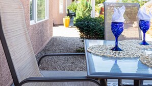 A patio with a table and chairs, a decorative wall, and a view of a house in the background. - Beautiful 2/2 in Springfield 55+ Golf Community 30 night minimum (Chandler)