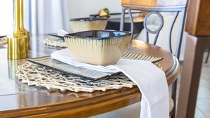 A dining table with ceramic bowls, a gold vase, and a woven placemat. - Beautiful 2/2 in Springfield 55+ Golf Community 30 night minimum (Chandler)