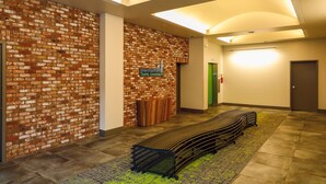 Un couloir avec un mur en briques, un comptoir d’accueil et un banc.