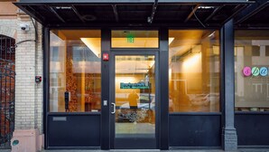 Une entrée d’immeuble avec une porte en verre, une enseigne indiquant « Rivertown Park Travel Apartments » et un détecteur d’incendie bien visible.