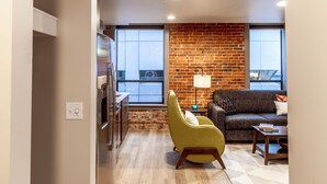 A modern living room with a brick accent wall, a sofa, a yellow armchair, and a coffee table.