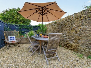 A patio with a table, chairs, and an umbrella. - Coach House - UK32202 (Burton Bradstock, near Bridport)