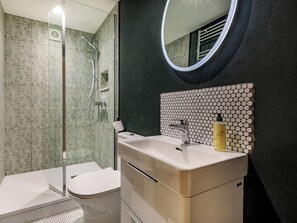 A bathroom with a shower, toilet, sink, and a mirror.