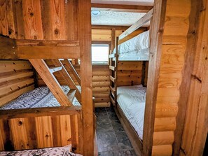 Eine Holzhütte mit Etagenbetten, geneigter Decke und einem Fenster.