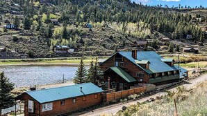 A cabin with a metal roof, situated near a lake, surrounded by forested hills. - LAKEFRONT FISHING LODGE RETREAT SLEEPS 50! BOAT RENTALS! WORLD CLASS FISHING! (Panguitch)