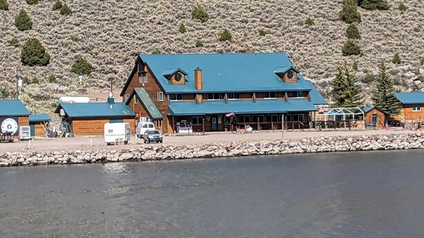 A large wooden lodge with a blue roof, situated by a rocky shore. - LAKEFRONT FISHING LODGE RETREAT SLEEPS 50! BOAT RENTALS! WORLD CLASS FISHING! (Panguitch)