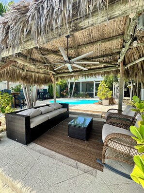 A covered outdoor seating area with a pool in the background. - SC1-Southern Comfort One at 310 11th St. In KCB. Private Pool & BEST Backyard.  (Key Colony Beach)